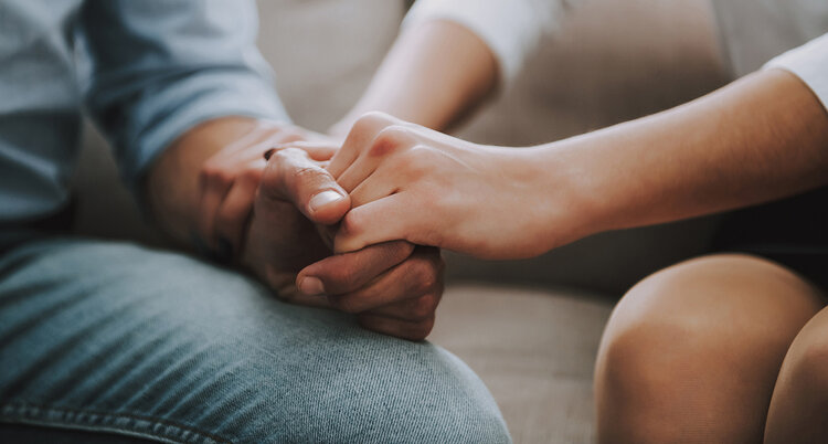 Close up. Man and woman hold hands tightly.