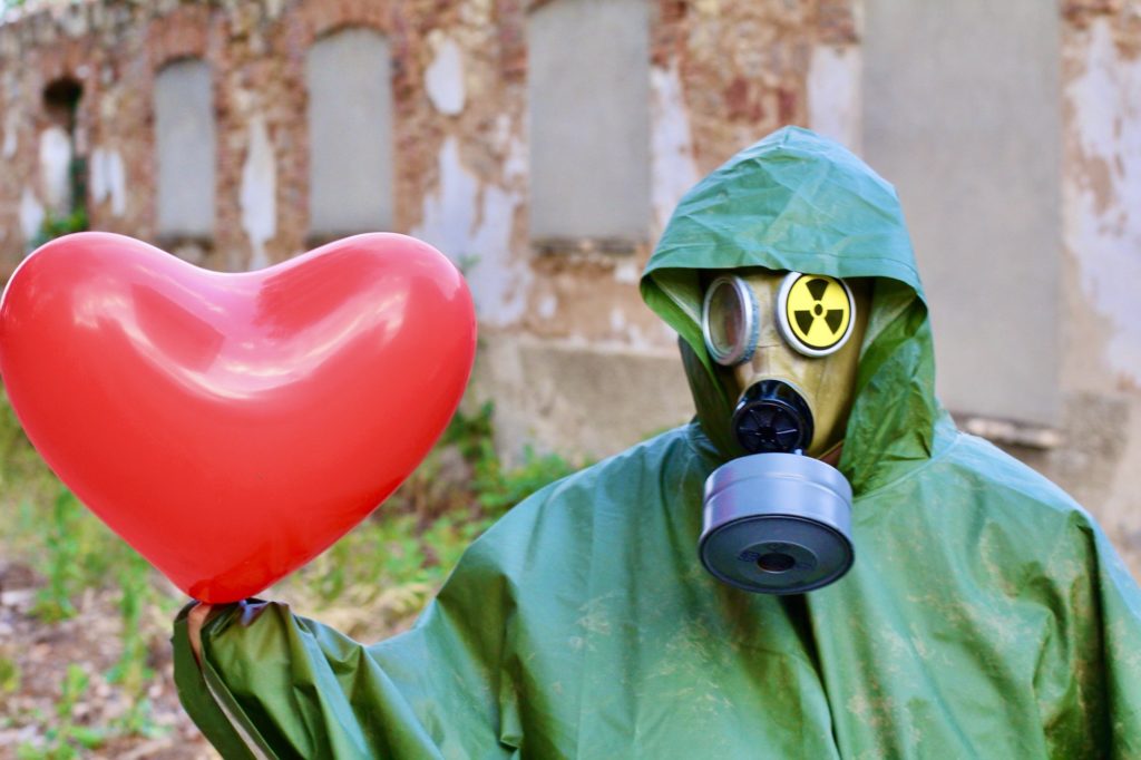 person wearing PPE kit showing heart balloon