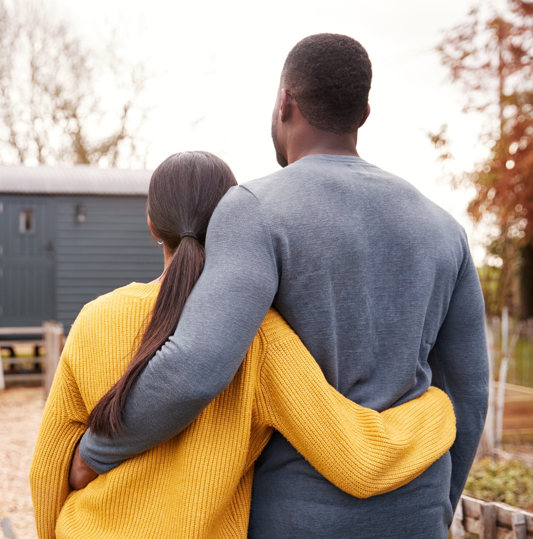Couple with arms around each other looking toward the future with hope and unity